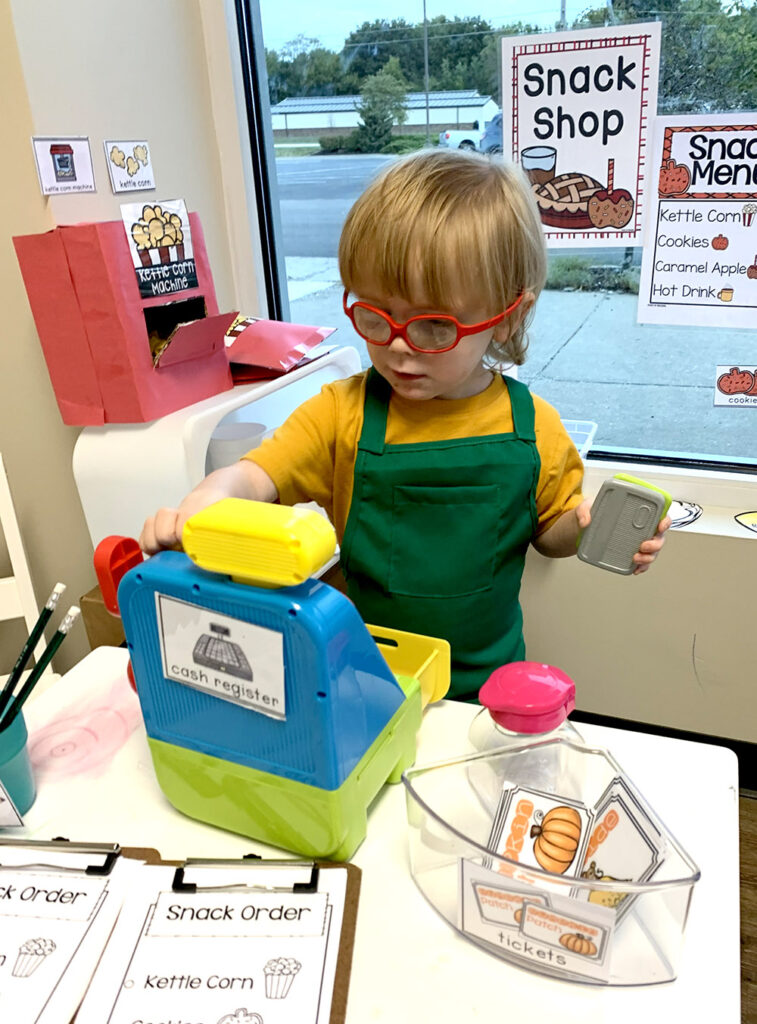 A boy playing with a toy cash register.