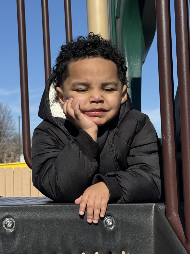 boy with hand on his chin sitting on playground equipment