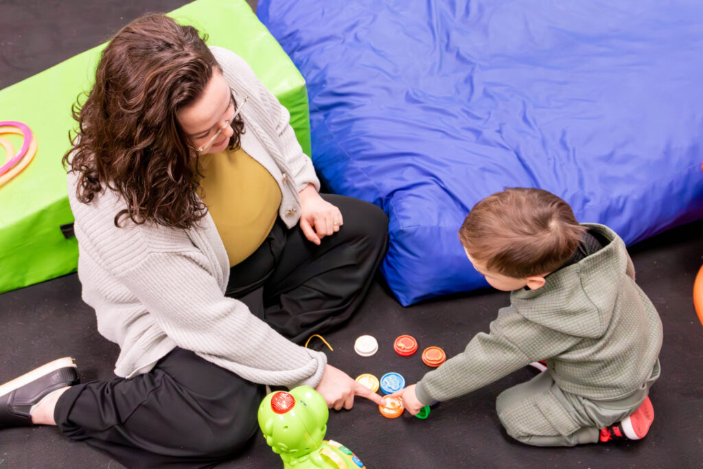 child in therapy session playing with green dinosaur toy